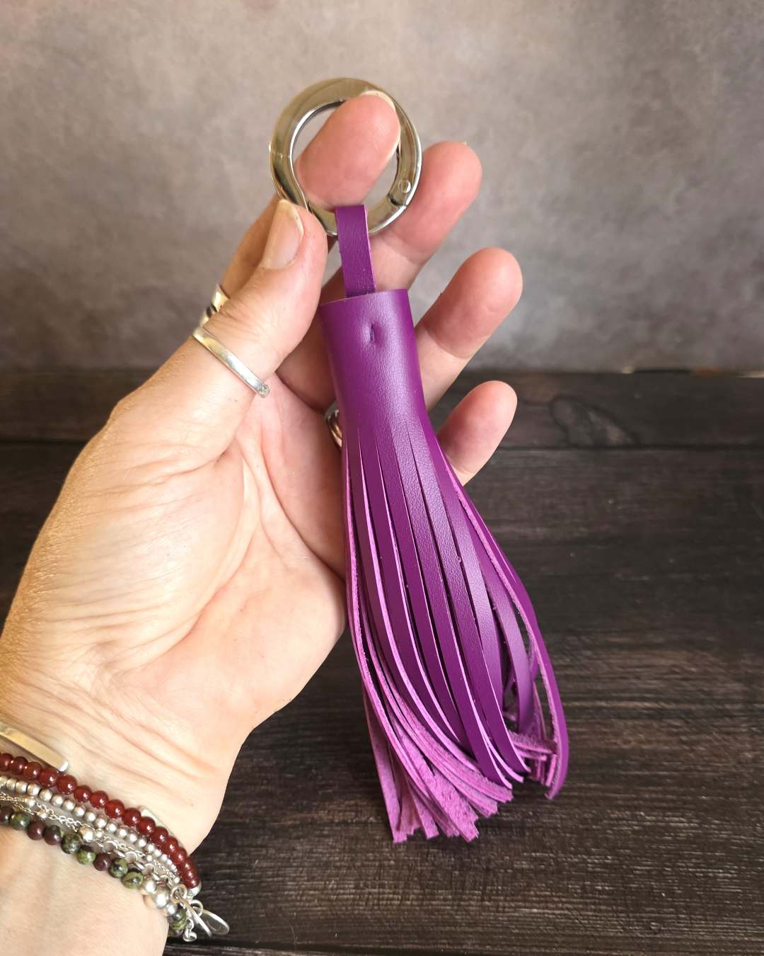 Porte-cle-pompon-en-cuir-violet Porte clé en cuir violet en forme de pompon long avec un anneau plat qui s'ouvre