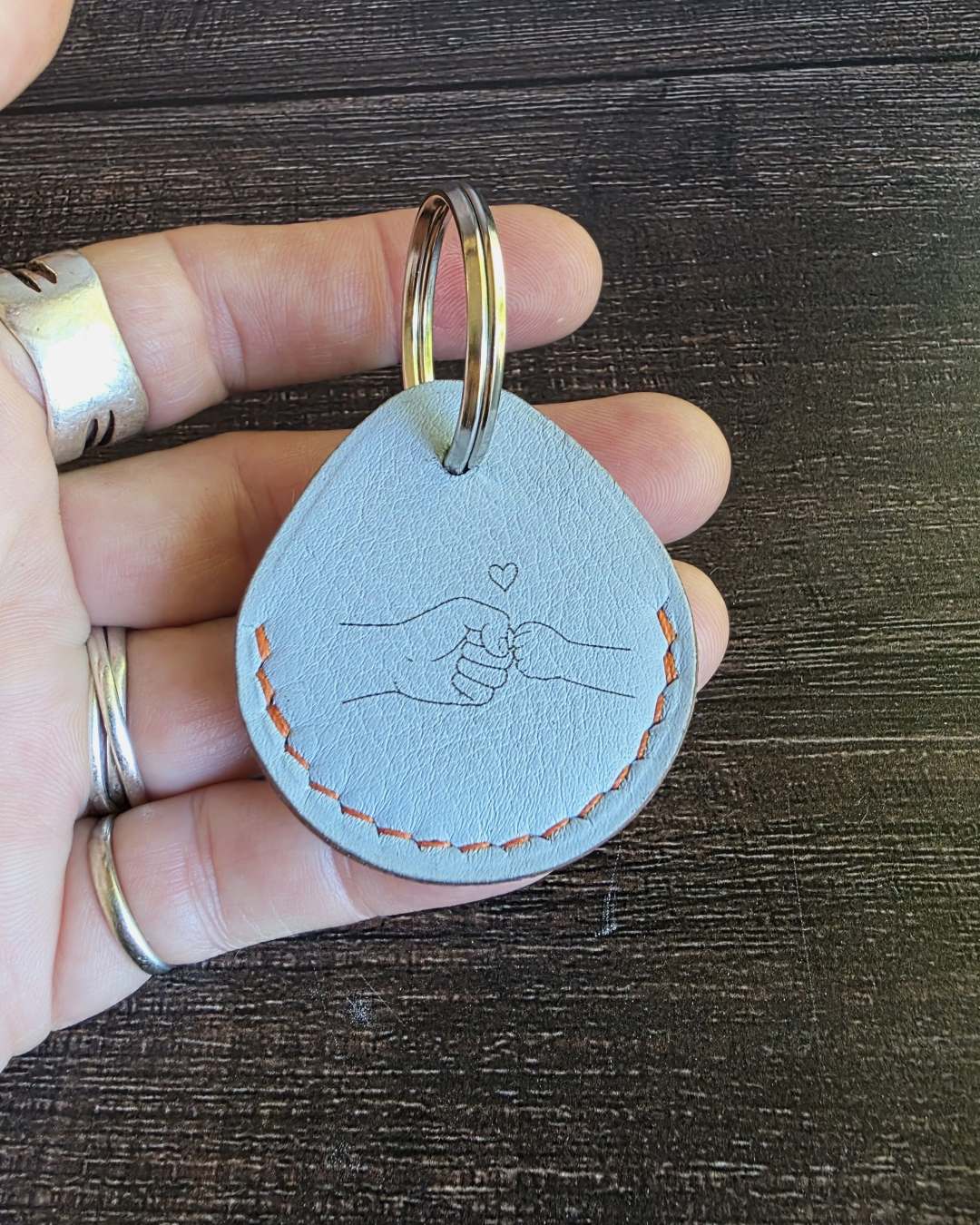 Porte-cle-en-cuir-bleu-personnalise Porte-clés gravé avec deux mains qui tchek sur un cuir fond bleu
